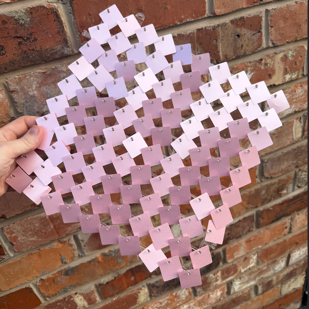 Pink sequin panel held against a brick wall